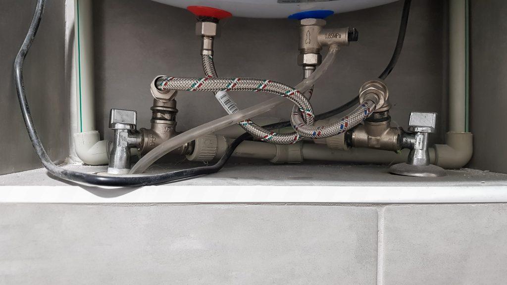 Connection of water supply, hot and cold water to the boiler. Hose for hot and cold water in the bathroom. Plumbing connections for a domestic electric water heater.